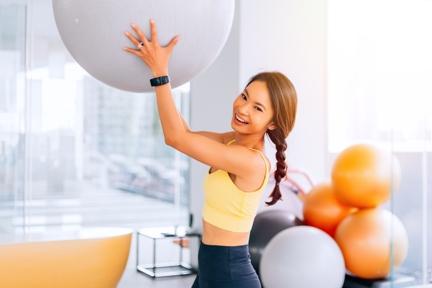 Portrait of Young Fit Asian Woman Holding Exercise Swiss Ball an